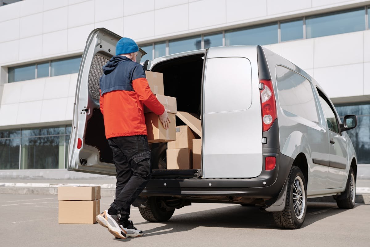 DoorDash driver loading delivery boxes into car trunk. Gig worker preparing for food deliveries. Tax deductible vehicle and delivery supplies.
