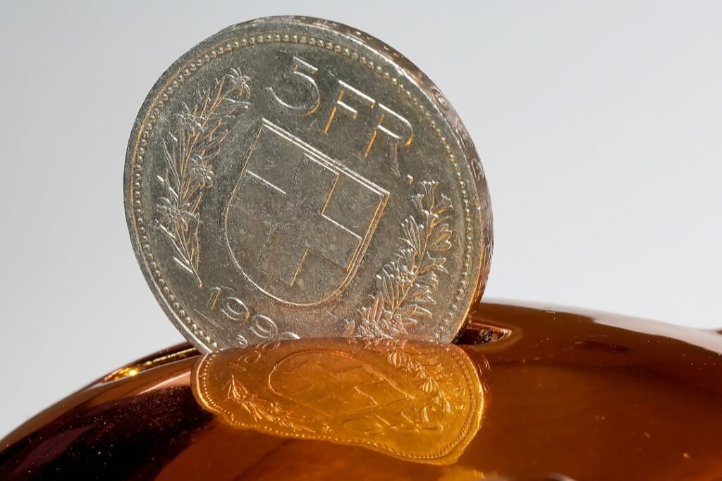 A coin being inserted into a piggy bank